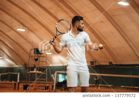 Man is playing tennis indoors in the hangar Man is playing tennis indoors in the hangar 137779572