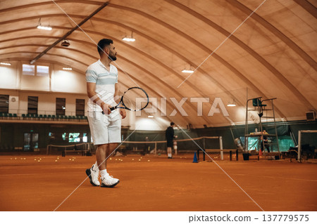 Side view, game in action. Man is playing tennis indoors in the hangar 137779575