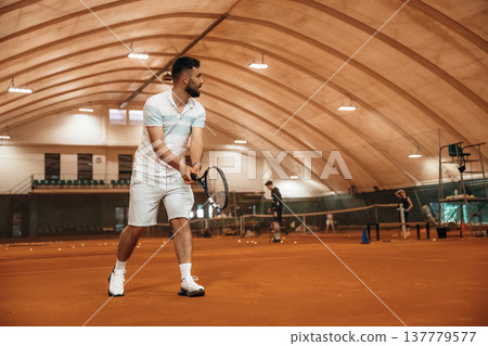 Side view, game in action. Man is playing tennis indoors in the hangar 137779577
