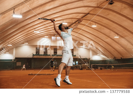 Man is playing tennis indoors in the hangar 137779588