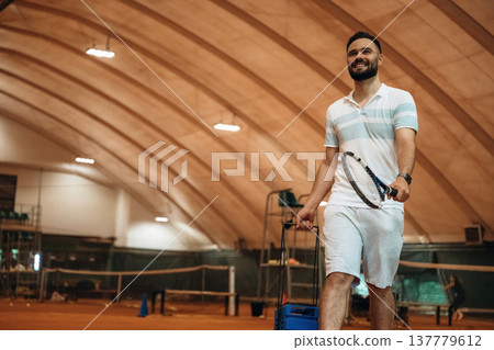 Smiling, positive facial expression. Man is playing tennis indoors in the hangar 137779612