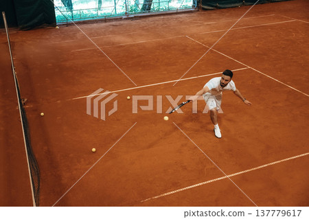 Top down view. Man is playing tennis indoors in the hangar Top down view. Man is playing tennis indoors in the hangar 137779617