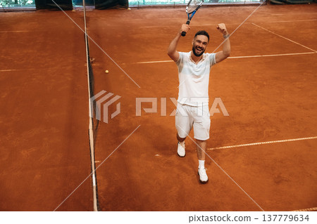 Celebrating victory, happy face. Man is playing tennis indoors in the hangar 137779634
