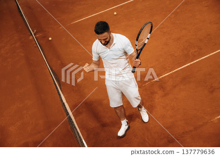 Celebrating victory, happy face. Man is playing tennis indoors in the hangar 137779636