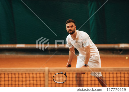 Front view. Man is playing tennis indoors in the hangar 137779659