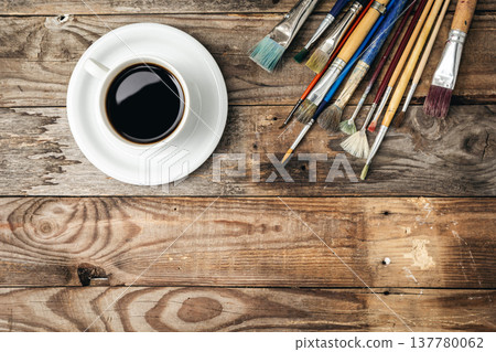 Paint brushes and a cup of coffee on a wooden background, flat lay. 137780062