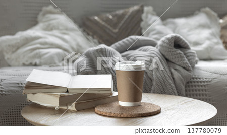 Paper cup and books in a cozy room interior, the concept of coziness. 137780079