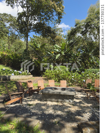 Seating area by the garden with stone fire pit under blue sky Seating area by the garden with stone fire pit under blue sky 137780131