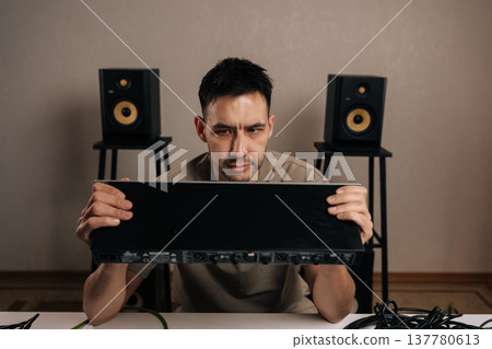 Sound engineer meticulously inspecting a studio audio processor with cables and monitor speakers, focusing on the intricate details of professional equipment setup and creative sound design. Sound engineer meticulously inspecting a studio audio processor with cables and monitor speakers, focusing on the intricate details of professional equipment setup and creative sound design. 137780613