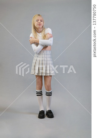 Posing with a plaid jacket, a girl in a white crop top and plaid skirt stands against a neutral background. This image reflects the fresh and trendy fashion choices of today's youth. Posing with a plaid jacket, a girl in a white crop top and plaid skirt stands against a neutral background. This image reflects the fresh and trendy fashion choices of today's youth. 137780750