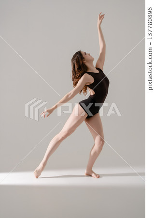 Young woman performing a graceful contemporary dance movement in a minimalist studio. 137780896
