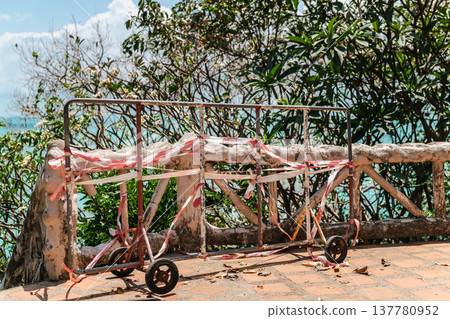Temporary safety barrier with warning tape on coastal viewpoint above tropical sea Temporary safety barrier with warning tape on coastal viewpoint above tropical sea 137780952