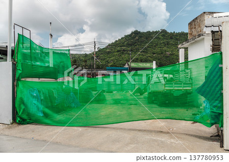 Construction site covered with green safety mesh netting in Lamai Koh Samui Thailand 137780953
