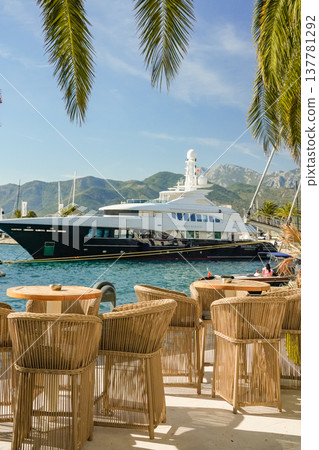 View of Yacht from Outdoor Cafe with Wicker Furniture and Palm Leaves View of Yacht from Outdoor Cafe with Wicker Furniture and Palm Leaves 137781292