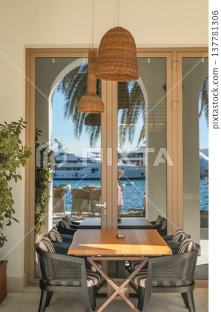 Wicker Chairs and Wooden Table with Hanging Lamps in Cafe Interior Wicker Chairs and Wooden Table with Hanging Lamps in Cafe Interior 137781306
