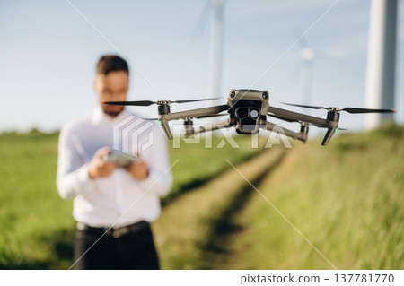 Focused photo of flying drone. Engineer in field checking on wind turbine production 137781770