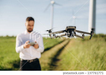 Focused photo of flying drone. Engineer in field checking on wind turbine production 137781771
