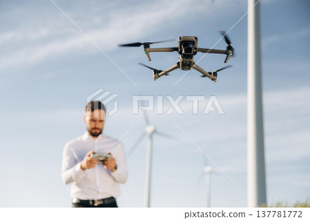 Focused photo of flying drone. Engineer in field checking on wind turbine production 137781772
