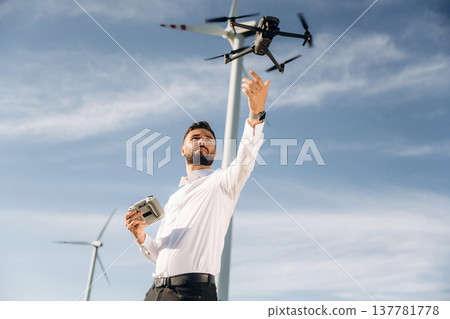 Catching a drone. Engineer in field checking on wind turbine production 137781778