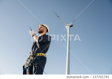 Using walkie talkie. Engineer in field checking on wind turbine production 137781791