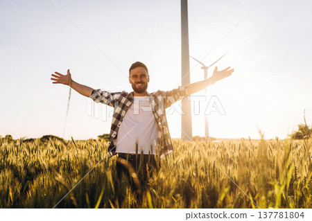 Hands to the sides, happy. Guy engineer in wheat field against wind turbines 137781804