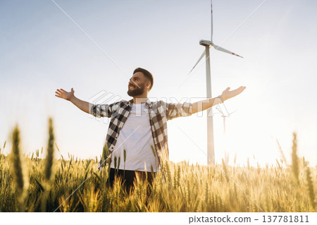 Freedom conception. Guy engineer in wheat field against wind turbines Freedom conception. Guy engineer in wheat field against wind turbines 137781811