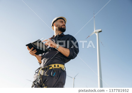Internet connection concept, with tablet. Engineer in field checking on wind turbine production Internet connection concept, with tablet. Engineer in field checking on wind turbine production 137781932