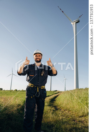 Employee is standing and posing. Engineer in field checking on wind turbine production Employee is standing and posing. Engineer in field checking on wind turbine production 137781953
