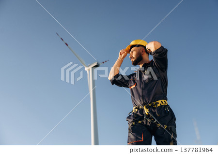 Break time, standing. Engineer in field checking on wind turbine production Break time, standing. Engineer in field checking on wind turbine production 137781964