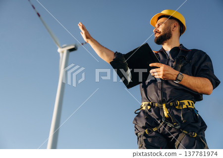 View from below, standing. Engineer in field checking on wind turbine production 137781974