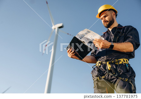 Documents in notepad. Engineer in field checking on wind turbine production Documents in notepad. Engineer in field checking on wind turbine production 137781975