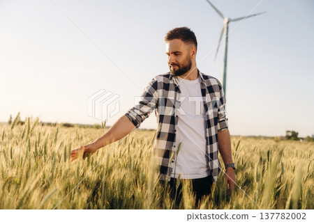 In checkered shirt. Guy engineer in wheat field against wind turbines 137782002