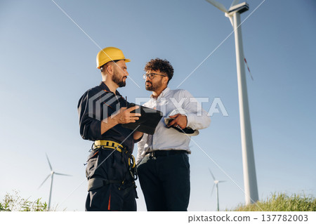 Making the business. Two men engineers are on field, with wind turbines Making the business. Two men engineers are on field, with wind turbines 137782003