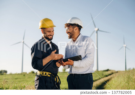 Cooperation concept. Two men engineers are on field, with wind turbines 137782005