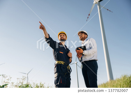 Making the business. Two men engineers are on field, with wind turbines Making the business. Two men engineers are on field, with wind turbines 137782007