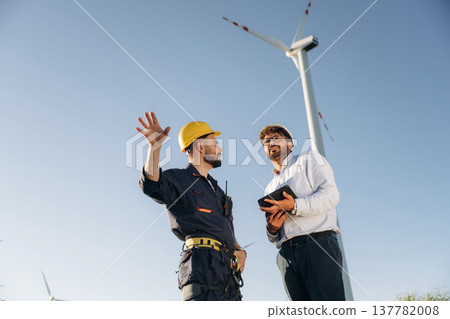 Making the business. Two men engineers are on field, with wind turbines 137782008