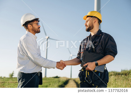 Cooperation concept. Two men engineers are on field, with wind turbines 137782016