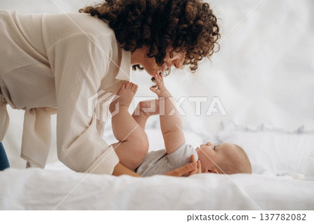 Parenting conception. Young woman is with her young baby daughter indoors Parenting conception. Young woman is with her young baby daughter indoors 137782082