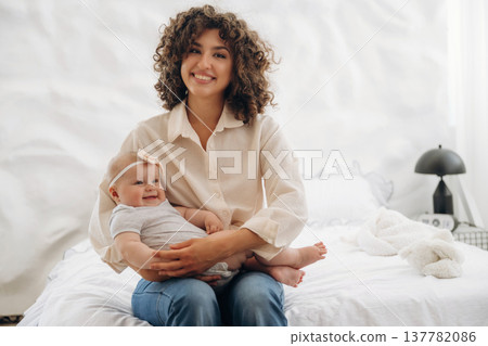 Young woman is with her young baby daughter indoors Young woman is with her young baby daughter indoors 137782086