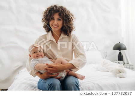 Young woman is with her young baby daughter indoors 137782087
