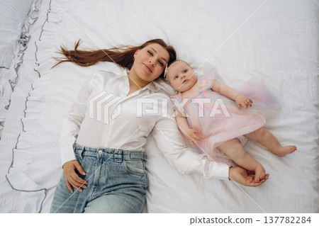 Top down view, lying down together. Happy mother is with her baby daughter indoors 137782284