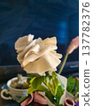 Macro View of Handmade White Fabric Rose with Layered Petals. Artisan Textile Floral Craft Detail for Sustainable Decor and DIY Inspiration. Close-up of Upcycled Cloth Blossom on Green Wired Stem. 137782376