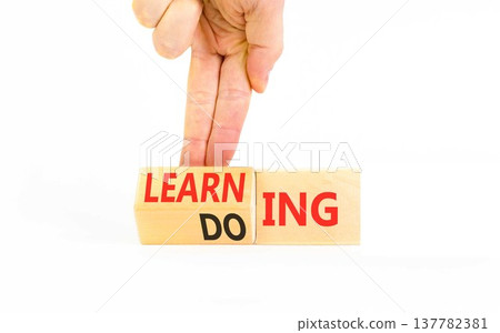 Doing or learning symbol. Concept words Doing to Learning on beautiful wooden cubes. Beautiful white background. Businessman's hand. Educational business doing or learning concept. Copy space 137782381