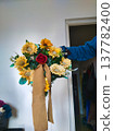 Rustic Sunflower and Red Rose Bouquet with Burlap Ribbon Held by Hand Indoors - Floral Arrangement Decor 137782400