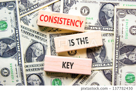 Consistency is the key symbol. Concept words Consistency is the key on beautiful wooden blocks. Beautiful dollar bills background. Dollar bills. Business consistency is the key concept. Copy space. 137782430