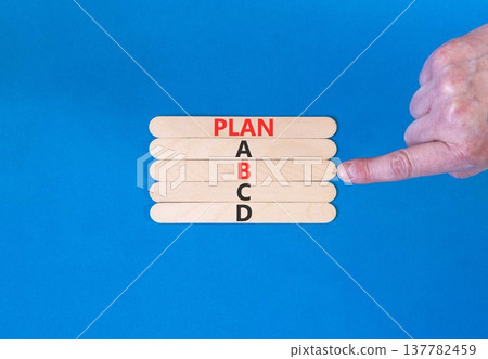 Time to plan B symbol. Concept word Plan A B C D on beautiful wooden sticks. Businessman's hand. Beautiful blue background. Business planning and time to plan B concept. Copy space. 137782459