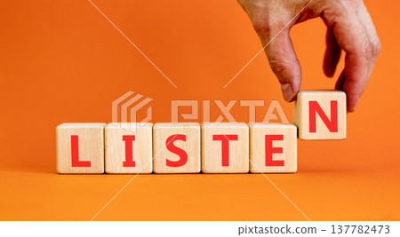 Listen symbol. Concept word Listen on beautiful wooden blocks. Beautiful orange background. Businessman's hand. Business education listen concept. Copy space. 137782473