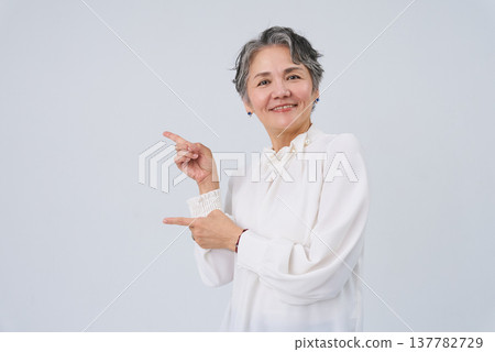 老年女性擺出像是在指路或提建議的姿勢。 老年女性擺出像是在指路或提建議的姿勢。 137782729