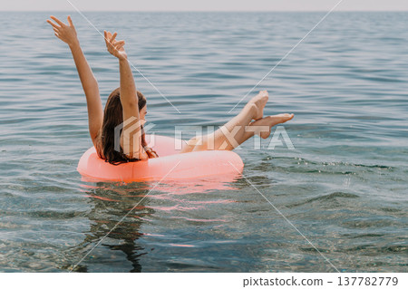 Woman floating inner tube water arms raised summer vacation sea 137782779