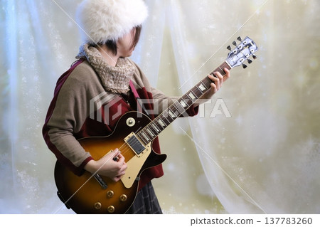 A woman wearing a white hat playing an electric guitar. 137783260